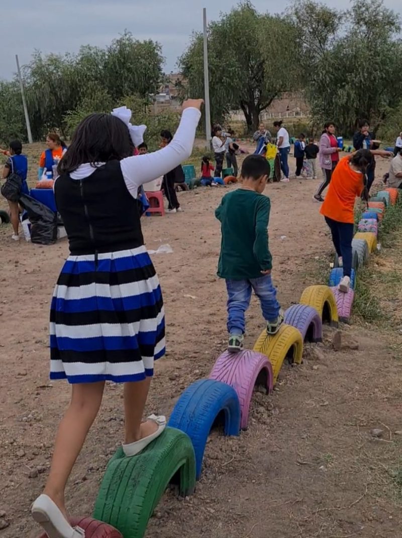 "Descubre la alegría de los niños jugando en un parque ecológico, donde el sendero de llantas recicladas pintadas ofrece una experiencia divertida y respetuosa con el medio ambiente. ¡Explora la sostenibilidad mientras disfrutas del juego al aire libre!"